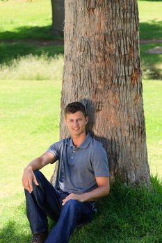 Man sitting beside a tree during the summer