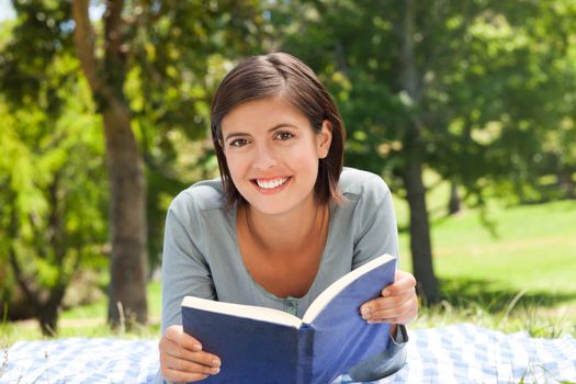Young woman reading a book in the park during the summer