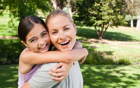 Mother and her daughter laughting in the park during the summer