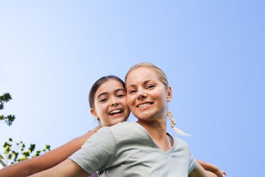 Mother and her daughter laughting in the park during the summer