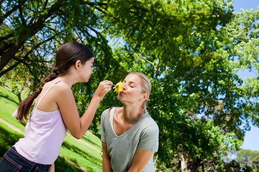 Mother and her daughter with a flower during the summer