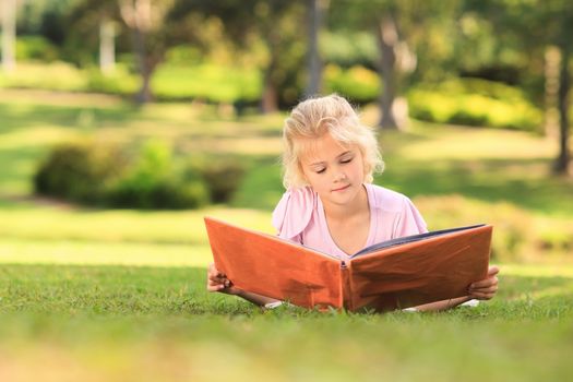 Little girl looking at her album photo during the summer