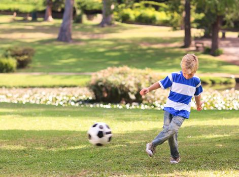 Boy playing football in the park during the summer