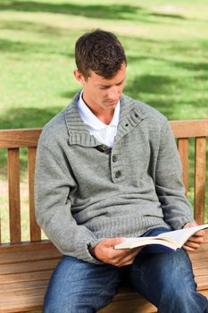 Man reading his book on the bench during the summer 