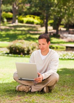 Man working on his laptop in the park during the summer 