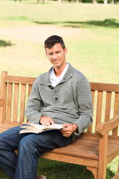 Man reading his book on the bench during the summer 