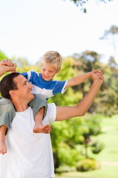 Man giving son a piggyback during the summer in a park