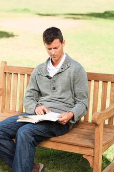 Man reading his book on the bench during the summer 