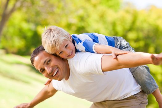 Son playing with his father in the park during the summer 