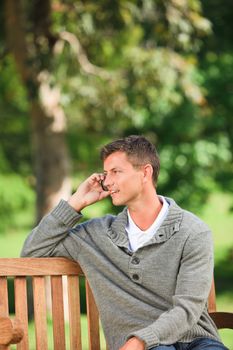 Man phoning on the bench during the summer 