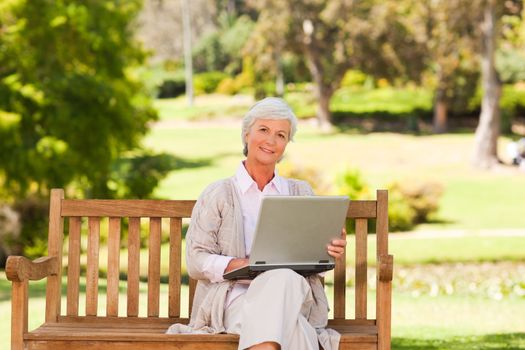 Retired woman working on her laptop during the summer in a park