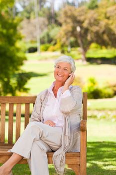 Elderly woman on a phone during the summer in a park