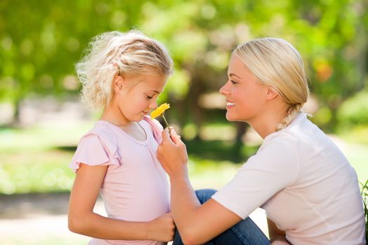 Mother and her daughter smelling a flower during the summer 