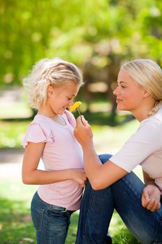Mother and her daughter smelling a flower in a park