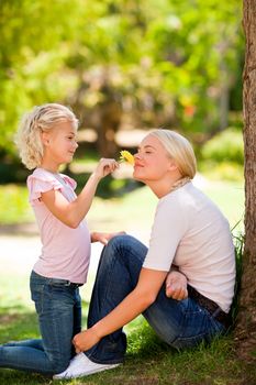 Mother and her daughter smelling a flower during the summer 