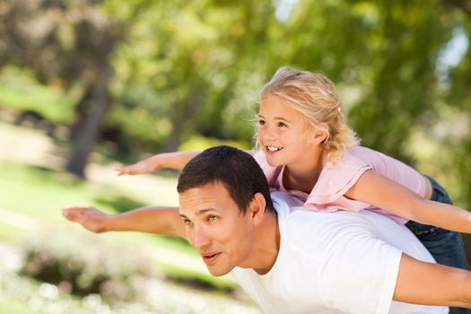 Little girl playing with her father during the summer in the park