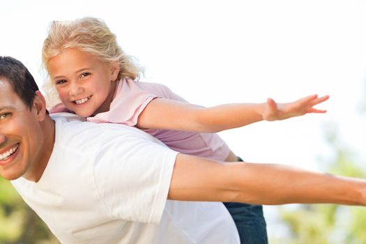 Little girl playing with her father in the park during the summer 