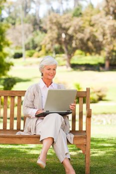 Retired woman working on her laptop in a park
