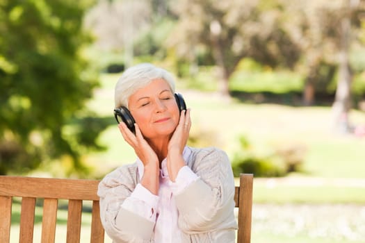 Senior woman listening to some music during the summer in a park
