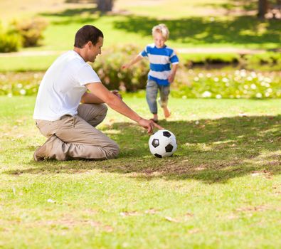 Father playing football with his son in a park