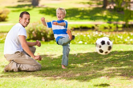 Father playing football with his son during the summer in a park