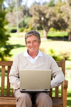 Senior man working on his laptop during the summer