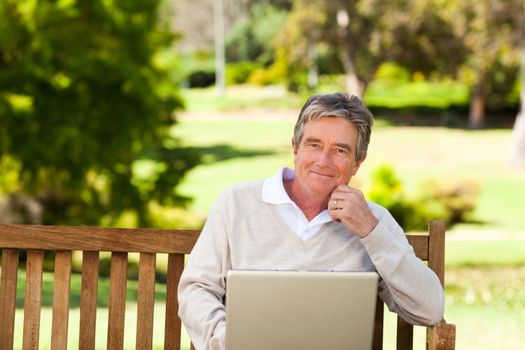 Senior man working on his laptop during the summer