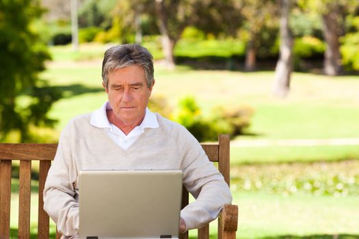 Senior man working on his laptop during the summer