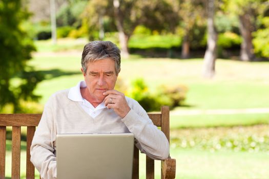 Senior man working on his laptop during the summer