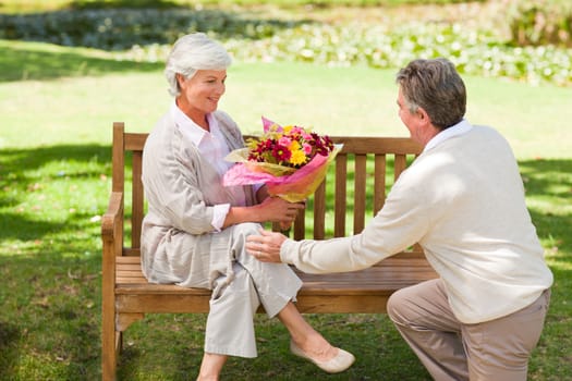 Senior man offering flowers to his wife during the summer