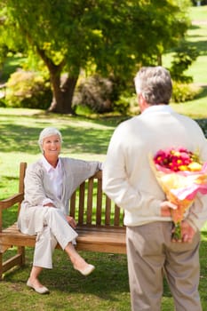Retired man offering flowers to his wife in a park