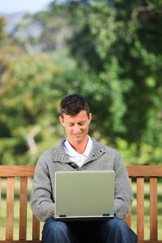 Man working on his laptop in the park during the summer 
