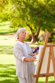 Senior woman painting in the park during the summer