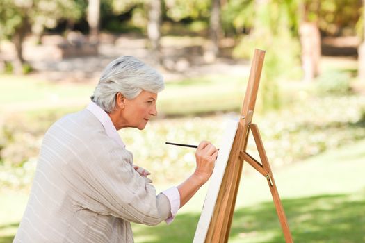 Mature woman painting in the park during the summer