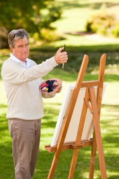 Elderly man painting in the park during the summer