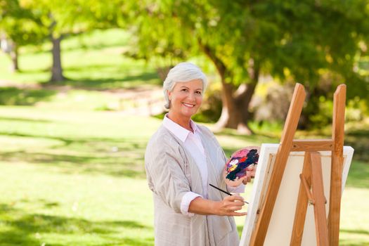 Senior woman painting in the park during the summer