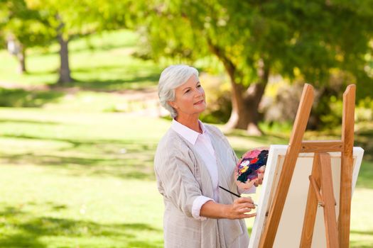 Senior woman painting in the park during the summer