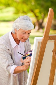 Mature woman painting in the park during the summer