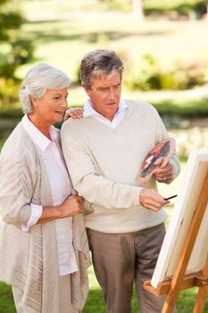 Retired couple painting in the park during the summer