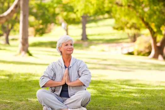 Mature woman practicing yoga in the park during the summer