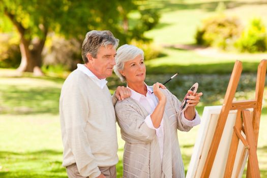 Retired couple painting in the park during the summer