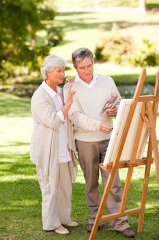 Retired couple painting in the park during the summer