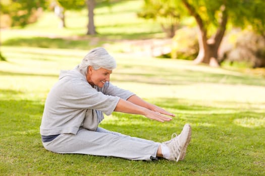 Retired woman doing her stretches in the park during the summer