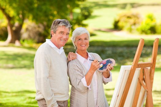 Senior couple painting in the park during the summer