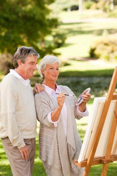 Senior couple painting in the park during the summer