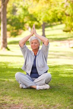 Senior woman practicing yoga in the park during the summer