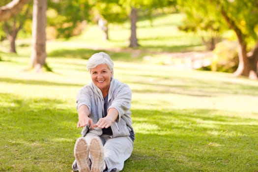 Retired woman doing her stretches in the park during the summer