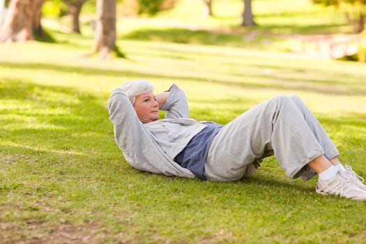 Retired woman doing her stretches in the park during the summer