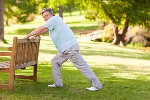 Retired man doing his stretches in the park during the summer