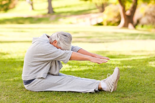 Retired woman doing her stretches in the park during the summer